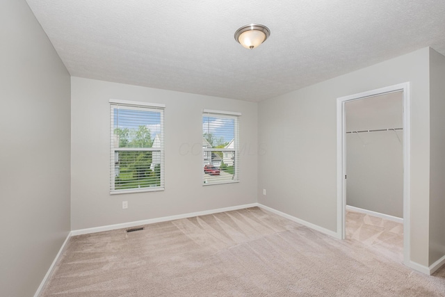 2357 Pine Crest Dr, Lancaster, OH 43130 - unfurnished bedroom with light colored carpet, a spacious closet, baseboards, a closet, and a textured ceiling