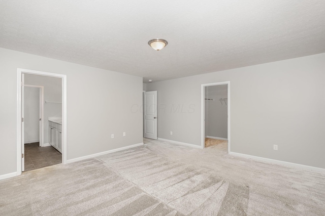 2357 Pine Crest Dr, Lancaster, OH 43130 - unfurnished bedroom with light carpet, a walk in closet, baseboards, a closet, and a textured ceiling