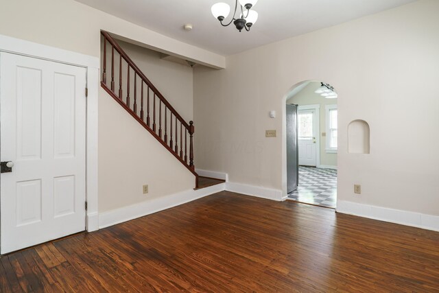 686 Hamlet St, Columbus, OH 43215 - unfurnished living room with arched walkways, wood finished floors, baseboards, stairs, and a chandelier