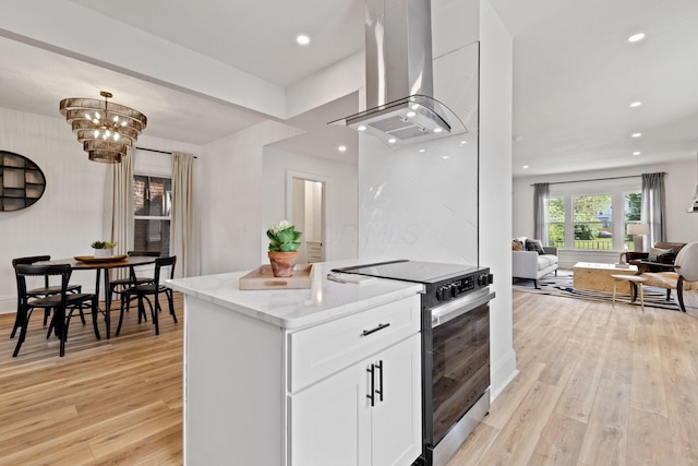 1104 E Whittier St, Columbus, OH 43206 - kitchen with range with electric stovetop, wall chimney range hood, light stone countertops, light wood-style floors, and white cabinetry