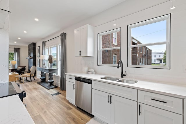 1104 E Whittier St, Columbus, OH 43206 - kitchen with stainless steel dishwasher, a sink, white cabinets, light wood finished floors, and recessed lighting