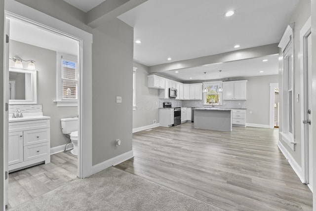 1093 E Long St, Columbus, OH 43203 - unfurnished living room with baseboards, recessed lighting, light wood finished floors, and a sink