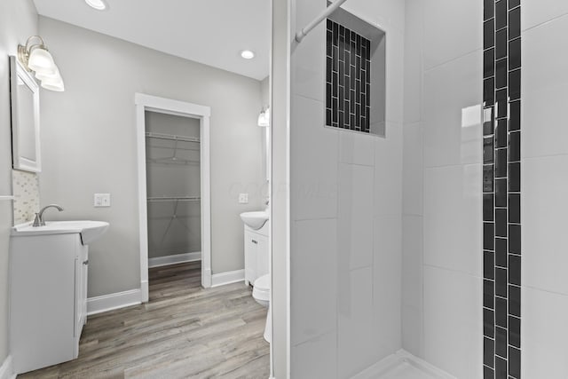 1093 E Long St, Columbus, OH 43203 - bathroom with wood finished floors, two vanities, baseboards, recessed lighting, and a tile shower