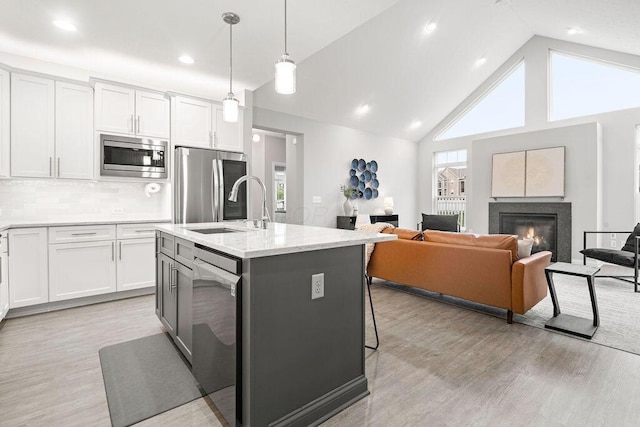 5165 Hamptonshire Dr, Dublin, OH 43016 - kitchen featuring appliances with stainless steel finishes, a sink, light wood-style flooring, white cabinetry, and high vaulted ceiling
