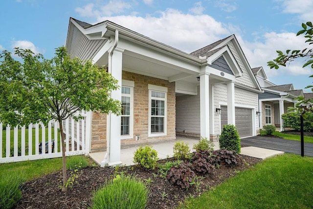 5165 Hamptonshire Dr, Dublin, OH 43016 - view of side of home featuring stone siding, an attached garage, and asphalt driveway