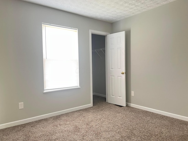 5966 Twin Pine Dr, New Albany, OH 43054 - unfurnished bedroom with carpet floors, baseboards, a walk in closet, a textured ceiling, and a closet