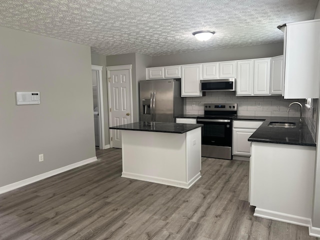 5966 Twin Pine Dr, New Albany, OH 43054 - kitchen featuring appliances with stainless steel finishes, a sink, wood finished floors, white cabinetry, and dark countertops