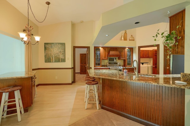 3695 Britton Ave, Columbus, OH 43204 - kitchen featuring appliances with stainless steel finishes, brown cabinets, a kitchen bar, a chandelier, and a towering ceiling