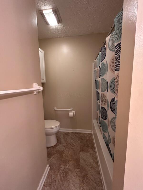 6855 Falcon Ln Unit 4A, Canal Winchester, OH 43110 - full bathroom with toilet, shower / tub combo, a textured ceiling, and baseboards