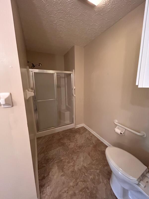 6855 Falcon Ln Unit 4A, Canal Winchester, OH 43110 - bathroom with a stall shower, toilet, a textured ceiling, and baseboards