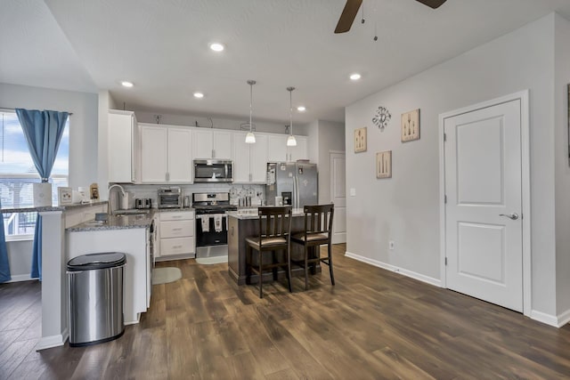 4196 Holstein Dr, Obetz, OH 43207 - kitchen featuring stainless steel appliances, ceiling fan, a kitchen bar, decorative backsplash, and white cabinetry