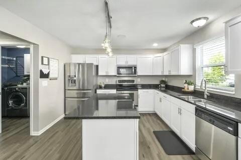 6004 Goldstone Dr, Grove City, OH 43123 - kitchen featuring appliances with stainless steel finishes, a sink, dark countertops, wood finished floors, and white cabinetry