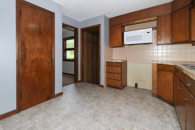 1266 Hanley Rd W, Mansfield, OH 44903 - kitchen with white microwave, light countertops, brown cabinets, and backsplash