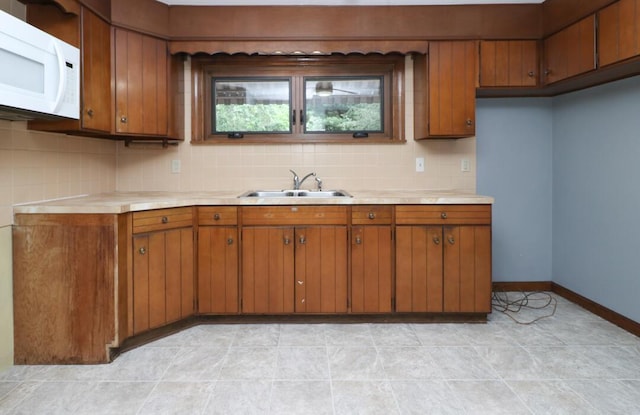 1266 Hanley Rd W, Mansfield, OH 44903 - kitchen featuring white microwave, a sink, light countertops, brown cabinetry, and backsplash