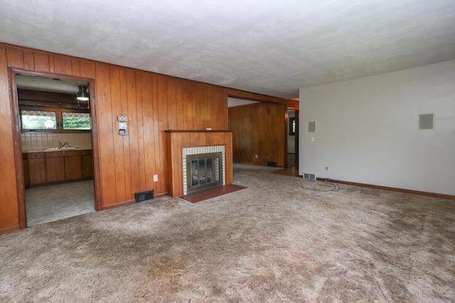 1266 Hanley Rd W, Mansfield, OH 44903 - unfurnished living room with a fireplace with flush hearth, a sink, wood walls, carpet, and baseboards