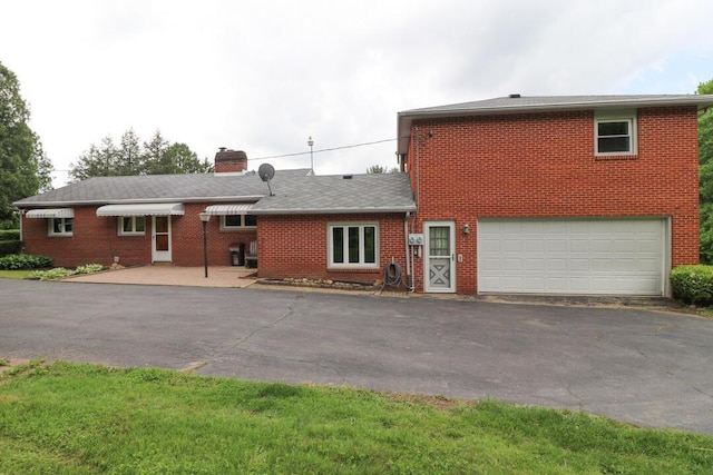 1266 Hanley Rd W, Mansfield, OH 44903 - view of front facade with brick siding, driveway, a chimney, and an attached garage