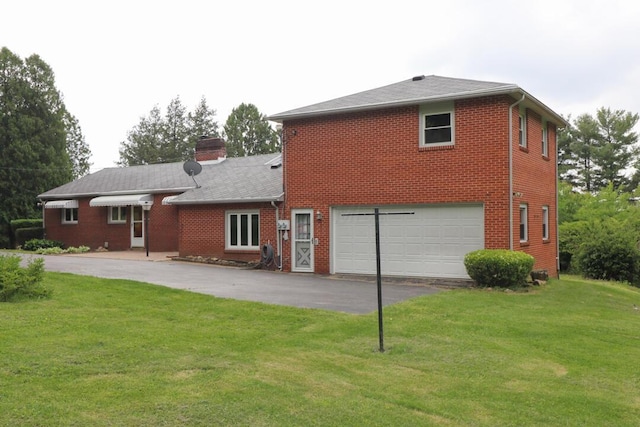 1266 Hanley Rd W, Mansfield, OH 44903 - back of house with driveway, a lawn, a garage, a chimney, and brick siding