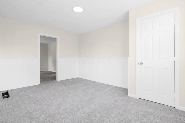spare room featuring wainscoting and carpet
