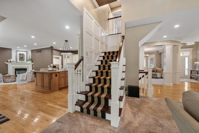 712 Riverbend Ave, Powell, OH 43065 - staircase featuring crown molding, wood finished floors, a decorative wall, recessed lighting, and a glass covered fireplace