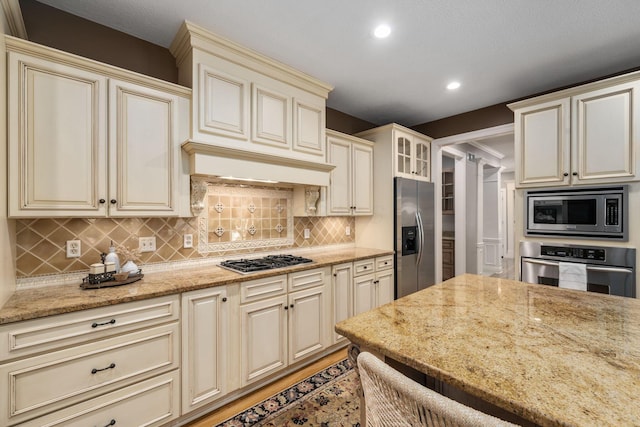 712 Riverbend Ave, Powell, OH 43065 - kitchen with appliances with stainless steel finishes, cream cabinetry, recessed lighting, light stone countertops, and tasteful backsplash