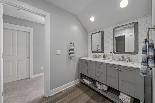 712 Riverbend Ave, Powell, OH 43065 - full bath with double vanity, lofted ceiling, baseboards, backsplash, and wood finished floors