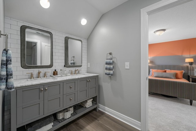 712 Riverbend Ave, Powell, OH 43065 - bathroom featuring double vanity, vaulted ceiling, baseboards, backsplash, and wood finished floors