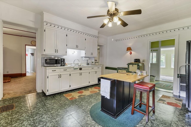 1625 Stringtown Rd NE, Lancaster, OH 43130 - kitchen featuring stainless steel microwave, white cabinets, a ceiling fan, a sink, and a kitchen bar