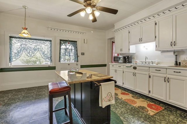 1625 Stringtown Rd NE, Lancaster, OH 43130 - kitchen featuring white cabinets, a sink, a ceiling fan, decorative light fixtures, and a kitchen breakfast bar