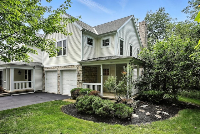 1223 Sanctuary Pl, Columbus, OH 43230 - traditional home featuring covered porch, a garage, asphalt driveway, stone siding, and a front lawn
