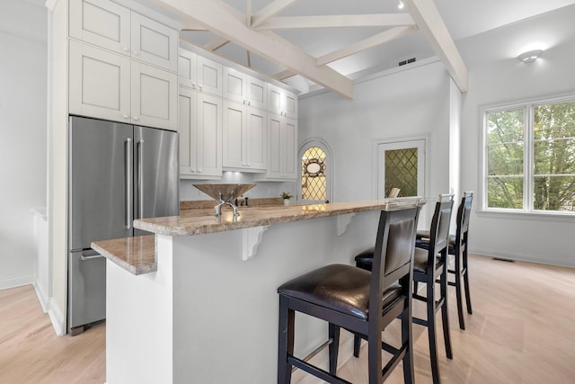 382 E Town St, Columbus, OH 43215 - kitchen featuring freestanding refrigerator, beam ceiling, light wood-style floors, baseboards, and light stone countertops