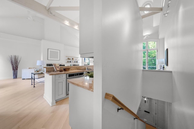 382 E Town St, Columbus, OH 43215 - kitchen featuring high vaulted ceiling, oven, light wood finished floors, light stone counters, and beam ceiling