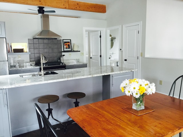 382 E Town St, Columbus, OH 43215 - kitchen with wall chimney range hood, a sink, light stone counters, a breakfast bar, and freestanding refrigerator
