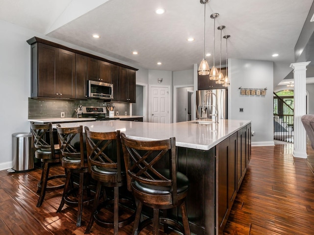 5046 Clark-Shaw Rd, Powell, OH 43065 - kitchen with stainless steel appliances, dark wood-style floors, baseboards, a spacious island, and dark brown cabinetry