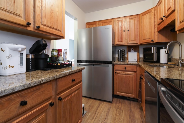 277 Lear St Unit 11, Columbus, OH 43206 - kitchen with appliances with stainless steel finishes, light wood-type flooring, a sink, and brown cabinets