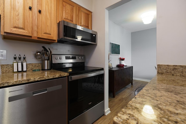 277 Lear St Unit 11, Columbus, OH 43206 - kitchen with appliances with stainless steel finishes, wood finished floors, light stone countertops, and brown cabinetry