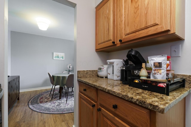 277 Lear St Unit 11, Columbus, OH 43206 - kitchen with wood finished floors, brown cabinetry, and light stone countertops