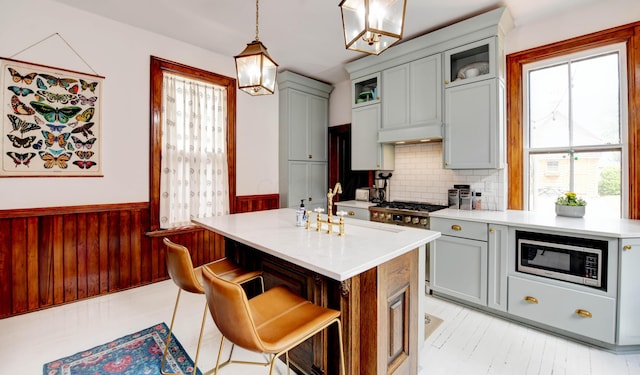 758 S Front St, Columbus, OH 43206 - kitchen with appliances with stainless steel finishes, a wainscoted wall, light countertops, gray cabinets, and a breakfast bar area