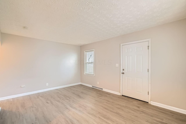 2454 Joyce Ave, Columbus, OH 43211 - empty room with a textured ceiling, light wood finished floors, and baseboards