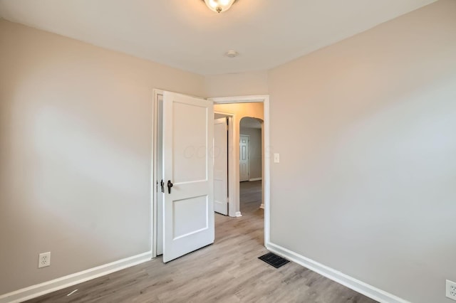 2454 Joyce Ave, Columbus, OH 43211 - spare room featuring baseboards, arched walkways, and light wood-style flooring