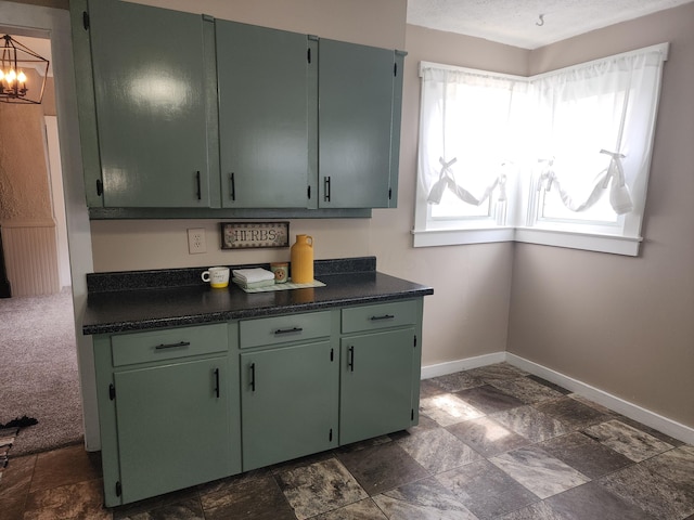 7703 County Road 91, Lewistown, OH 43333 - kitchen with baseboards, dark stone finish flooring, dark countertops, a chandelier, and green cabinetry