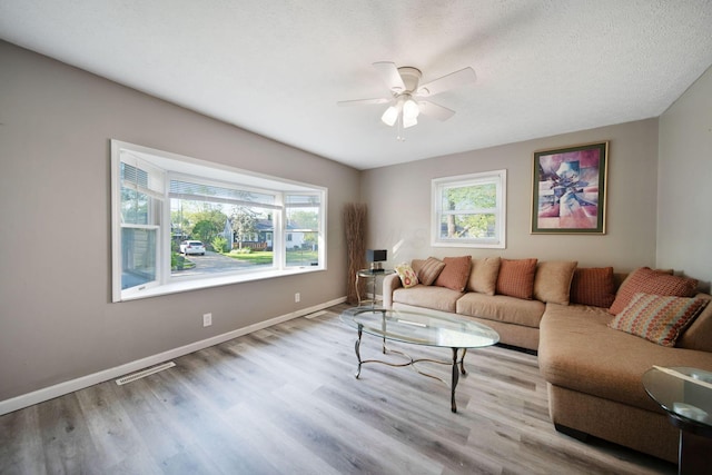 living area with a ceiling fan, baseboards, and wood finished floors