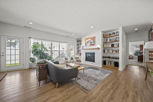 3918 Logan Ct, Hilliard, OH 43026 - living room with a textured ceiling, a glass covered fireplace, recessed lighting, wood finished floors, and built in shelves