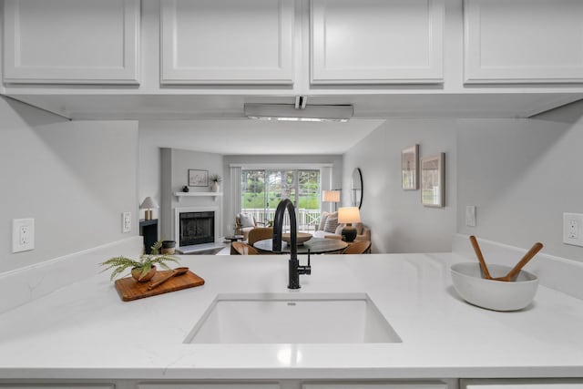 5394 Ambrosia Ave Unit 21B, Columbus, OH 43235 - kitchen with a sink, open floor plan, a fireplace with raised hearth, white cabinetry, and light stone countertops