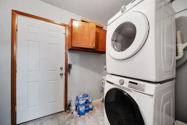 4861 Warminster Dr, Columbus, OH 43232 - laundry area featuring stacked washer and clothes dryer, cabinet space, baseboards, a textured ceiling, and light tile patterned flooring