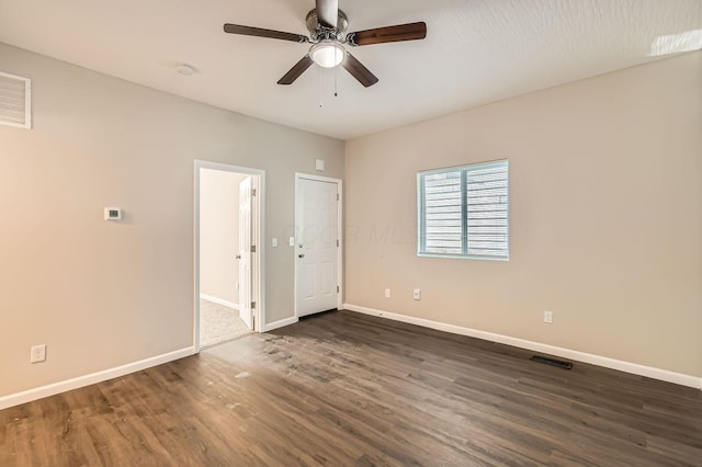 spare room with dark wood finished floors, baseboards, and a ceiling fan