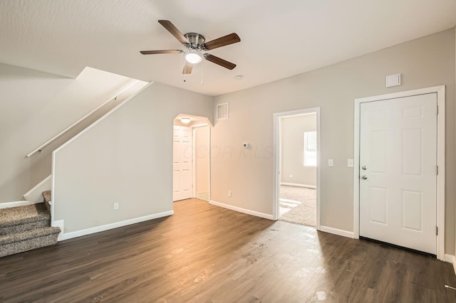 unfurnished living room with ceiling fan, baseboards, wood finished floors, stairs, and arched walkways