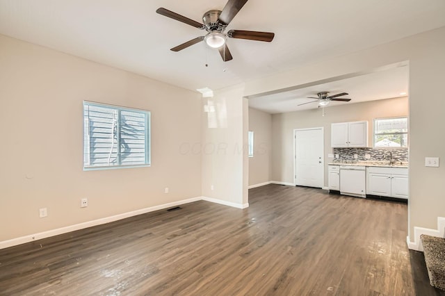 unfurnished living room featuring ceiling fan, dark wood-style flooring, and baseboards