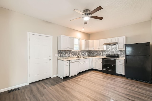 kitchen featuring black appliances, under cabinet range hood, ceiling fan, wood finished floors, and decorative backsplash