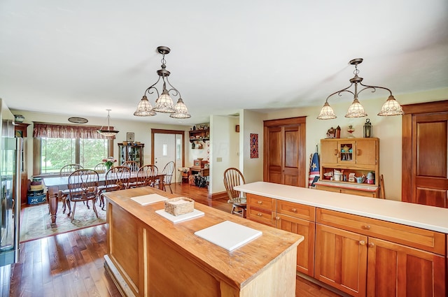 13742 State Rte 41, Jeffersonville, OH 43128 - kitchen featuring butcher block counters, wood finished floors, pendant lighting, a kitchen island, and brown cabinetry