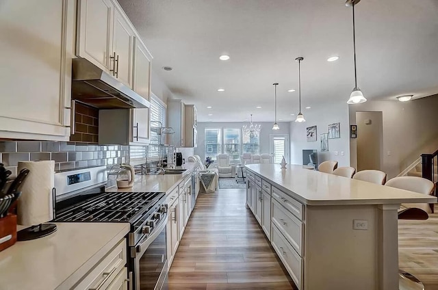 12281 Rooster Tail Dr, Pickerington, OH 43147 - kitchen featuring stainless steel gas range oven, under cabinet range hood, a kitchen bar, light wood finished floors, and open floor plan